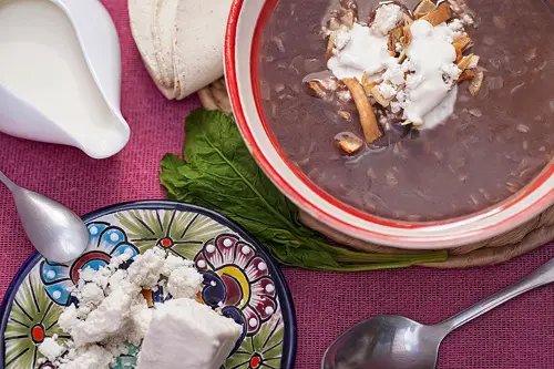 Sopa de Frijol Negro con crema, queso y tiras de totopos